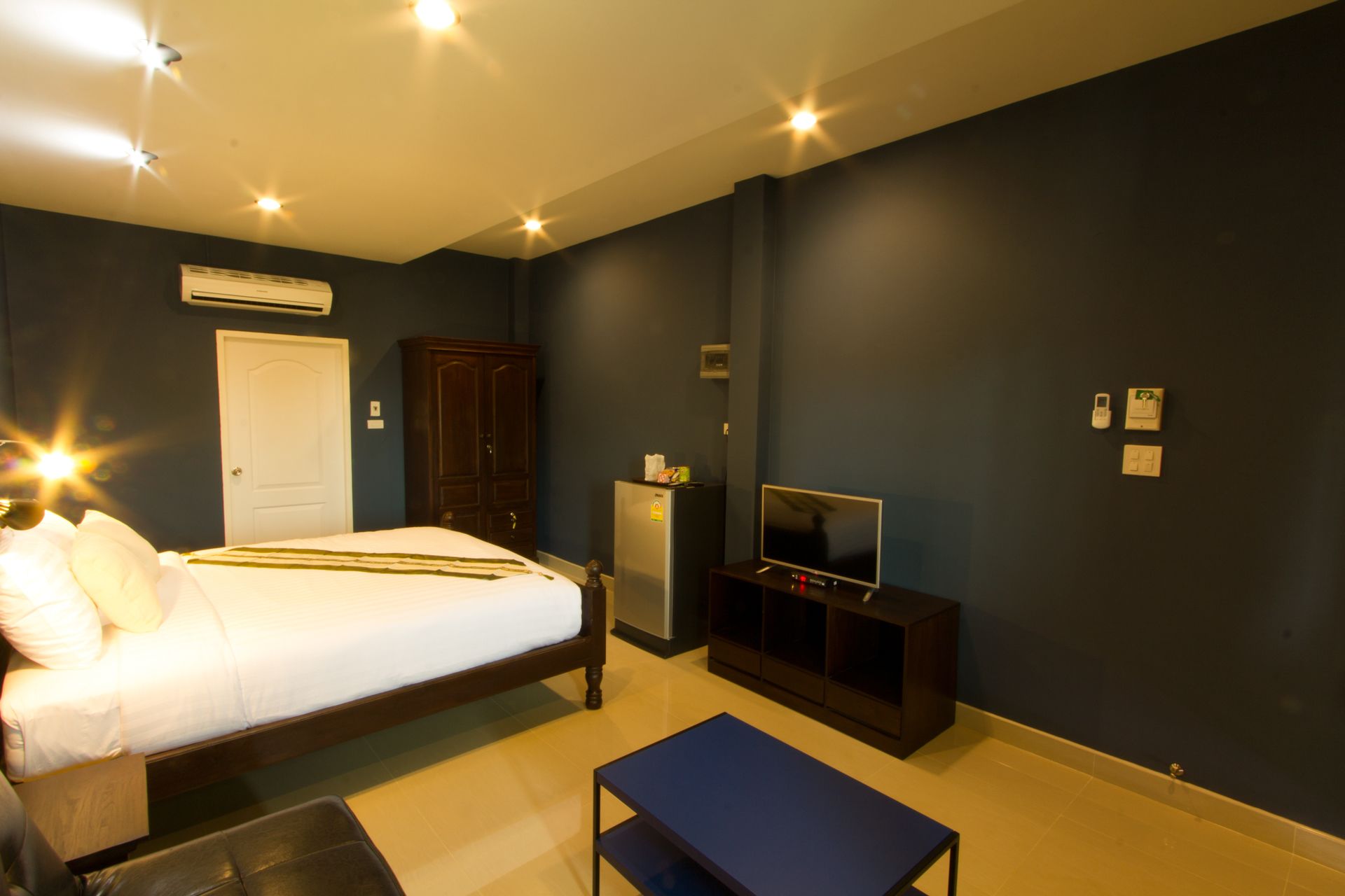 Un dormitorio con cama, televisión, armario y una mesita.