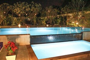 A swimming pool at night with surrounding vegetation and ambient lighting. - Kanvela Resort (Kanchanaburi)