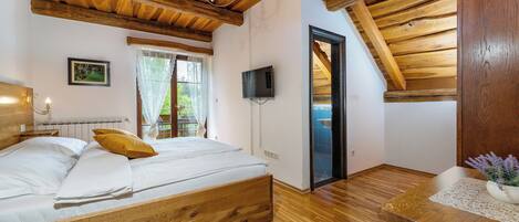 Een slaapkamer met een houten bed, een kroonluchter, een televisie en uitzicht op de omgeving.