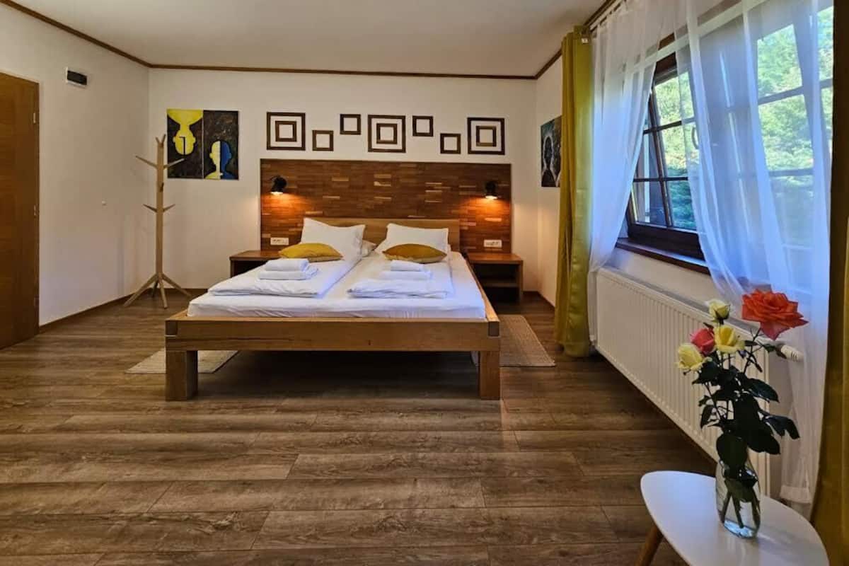 A bedroom with a wooden bed, two bedside tables, a floor lamp, and a window with curtains.