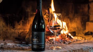 A bottle of Miraz Syrah 2018 wine and a glass of wine in front of a fireplace.