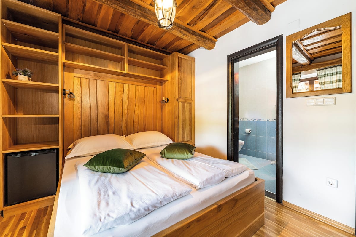 A wooden-framed bedroom with a bed, bedside tables, and a built-in wardrobe.