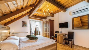 A bedroom with a wooden ceiling, a bed, a desk, a chair, and a TV on the wall. - Plitvica Lodge (Plitvicka Jezera)
