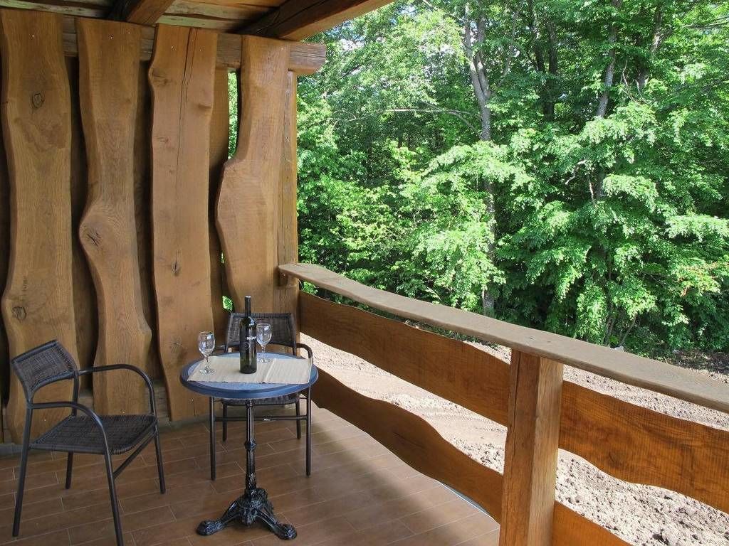 Un terrazzo in legno con tavolo e sedie, affacciato su una zona boschiva.