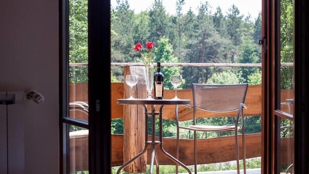 A balcony with a table set for two, a bottle of wine, and two glasses. - Plitvica Lodge (Plitvicka Jezera)