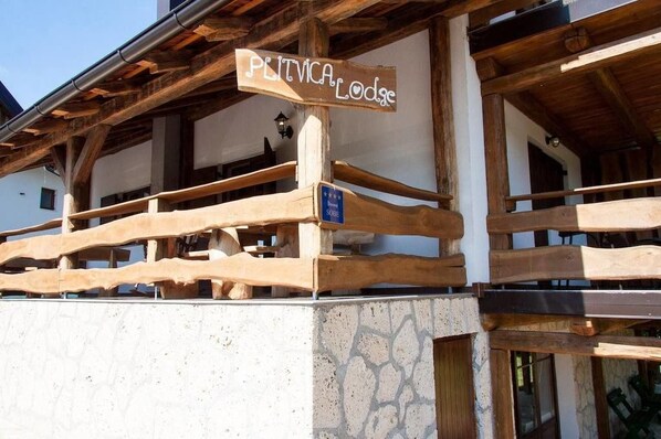 Un balcón de madera con un letrero que dice "PLITVICA Lodge".