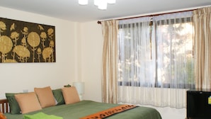 Una habitación de hotel con cama, almohadas, una colcha, televisión y un cuadro en la pared.