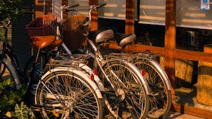 A bicycle parked outside a building with a wooden door and windows. - Happynest Inspiring Hostel (Chiang Rai)