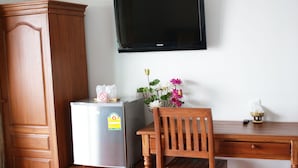 A room with a wooden wardrobe, a refrigerator, a wooden desk with a chair, a television mounted on the wall, and a vase with flowers. - Tara Raft Kanchanaburi (Kanchanaburi)