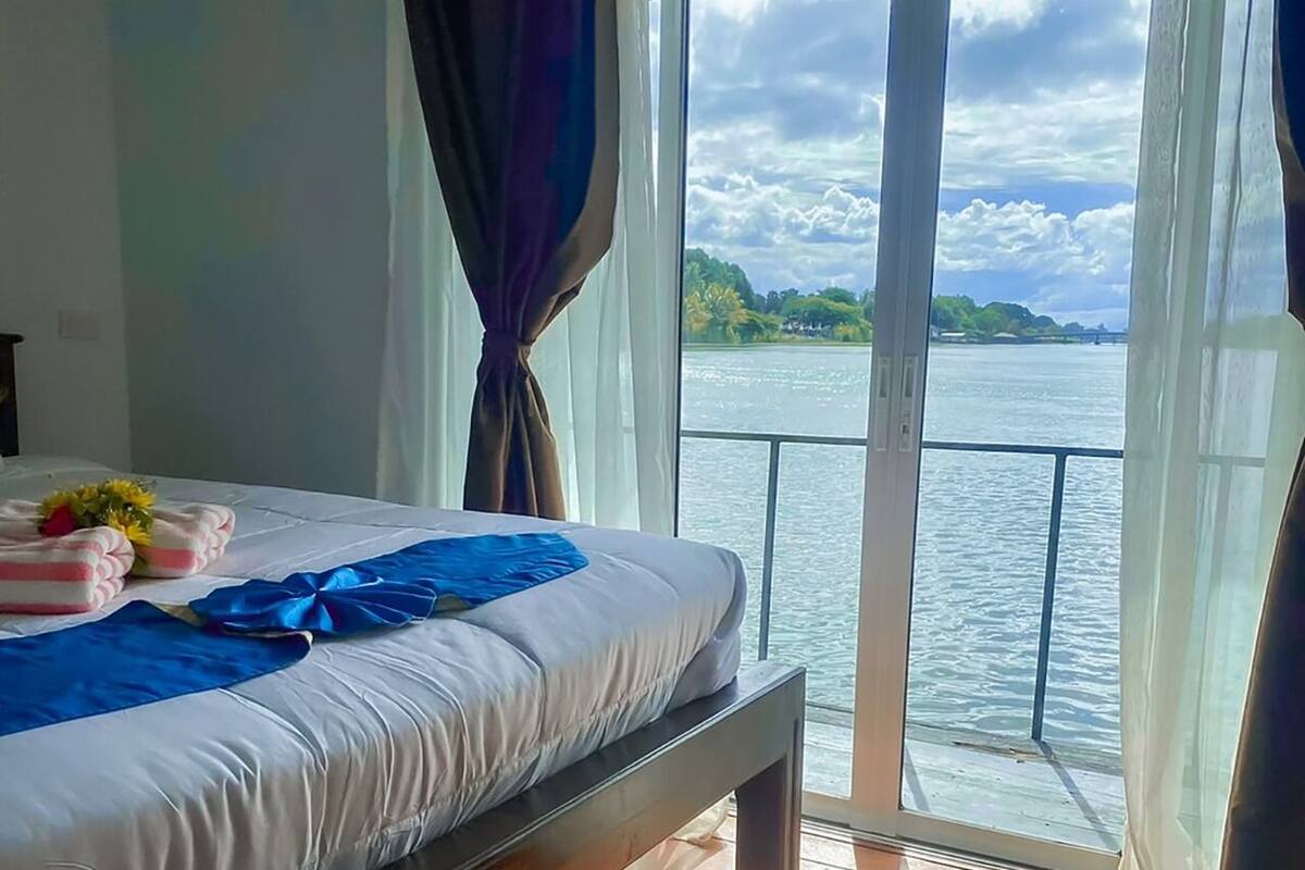 A hotel room with a bed, a view of the water, and a balcony.