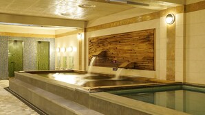 A spa area with a hot tub, a wooden wall panel, and a tiled wall with a green mosaic.