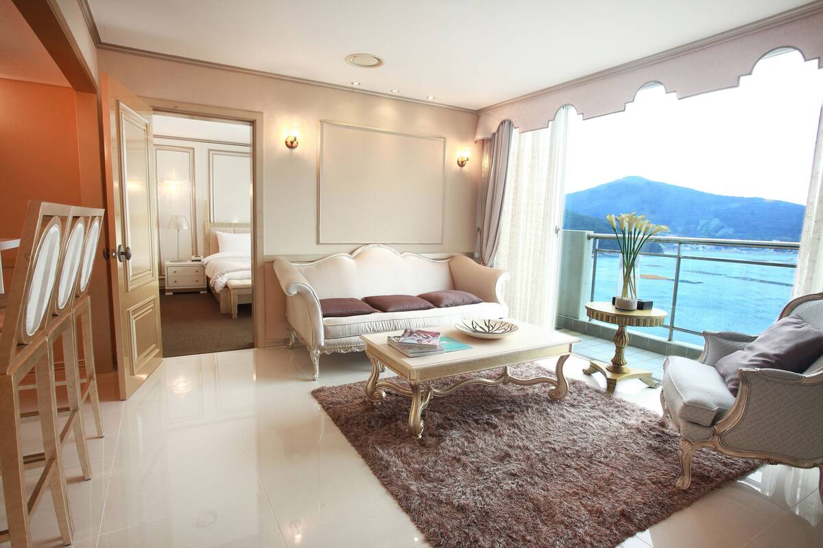 A spacious living room with a white sofa, a coffee table, and a view of the sea.
