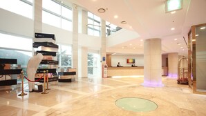 A spacious lobby with a reception desk, a glass elevator, and a modern design.