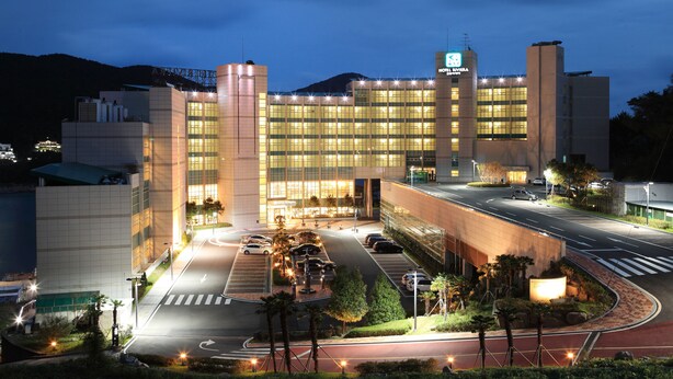 A modern hotel with a large glass facade, multiple floors, and a well-lit entrance.