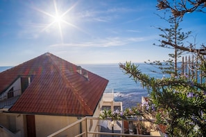 A coastal view with a red-roofed building, a clear sky, and the ocean in the background. - Appartamento Profumo di Mare (Cipressa)
