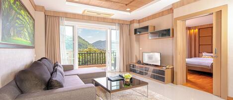Una habitación de hotel moderna con sofá, televisión y balcón con vistas a la montaña.