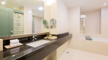 A modern bathroom with a black countertop, two sinks, a large mirror, and a bathtub.