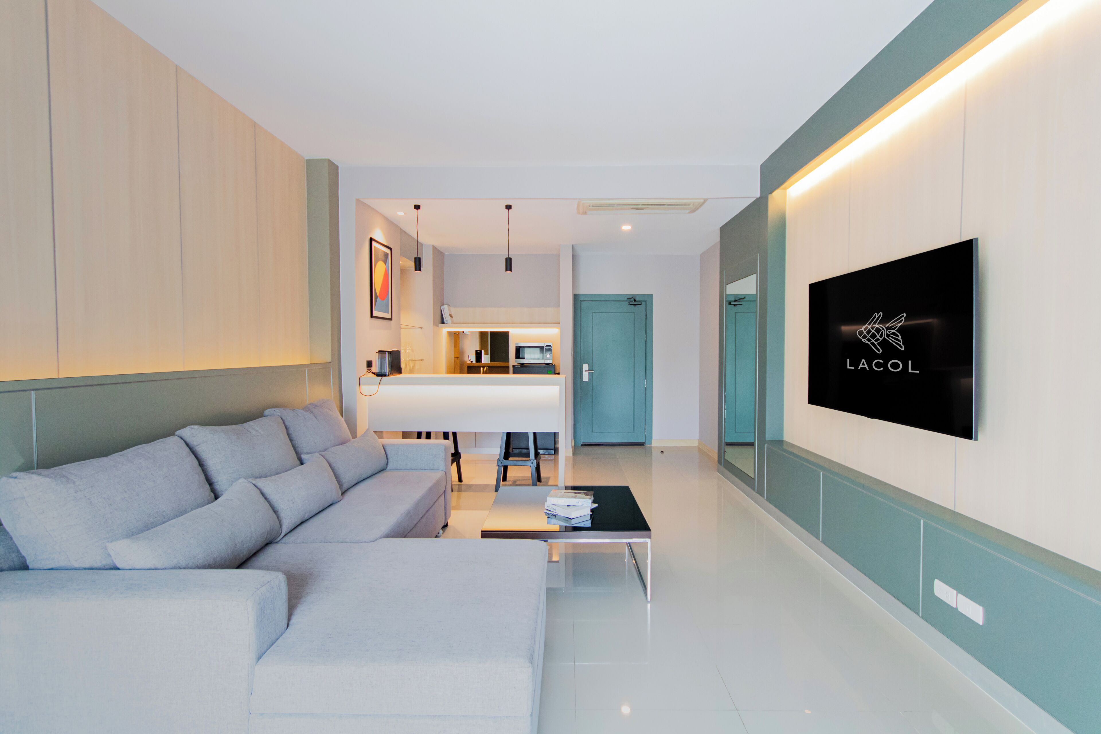 A modern living room with a sofa, a coffee table, and a TV mounted on the wall.