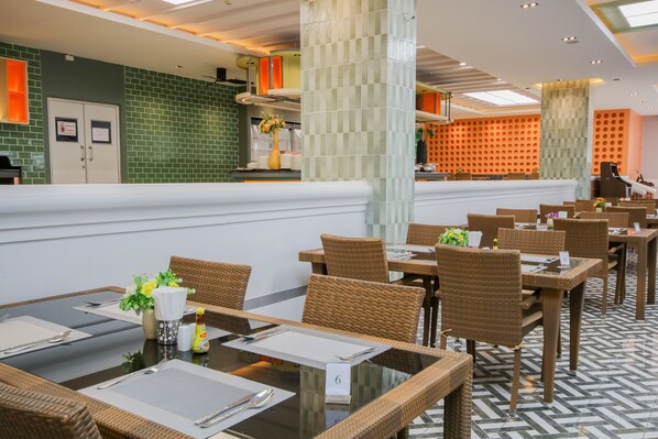 A restaurant with wicker tables and chairs, a tiled floor, and a green brick wall. - Lacol Khao Yai - A Chatrium Collection (Pak Chong)