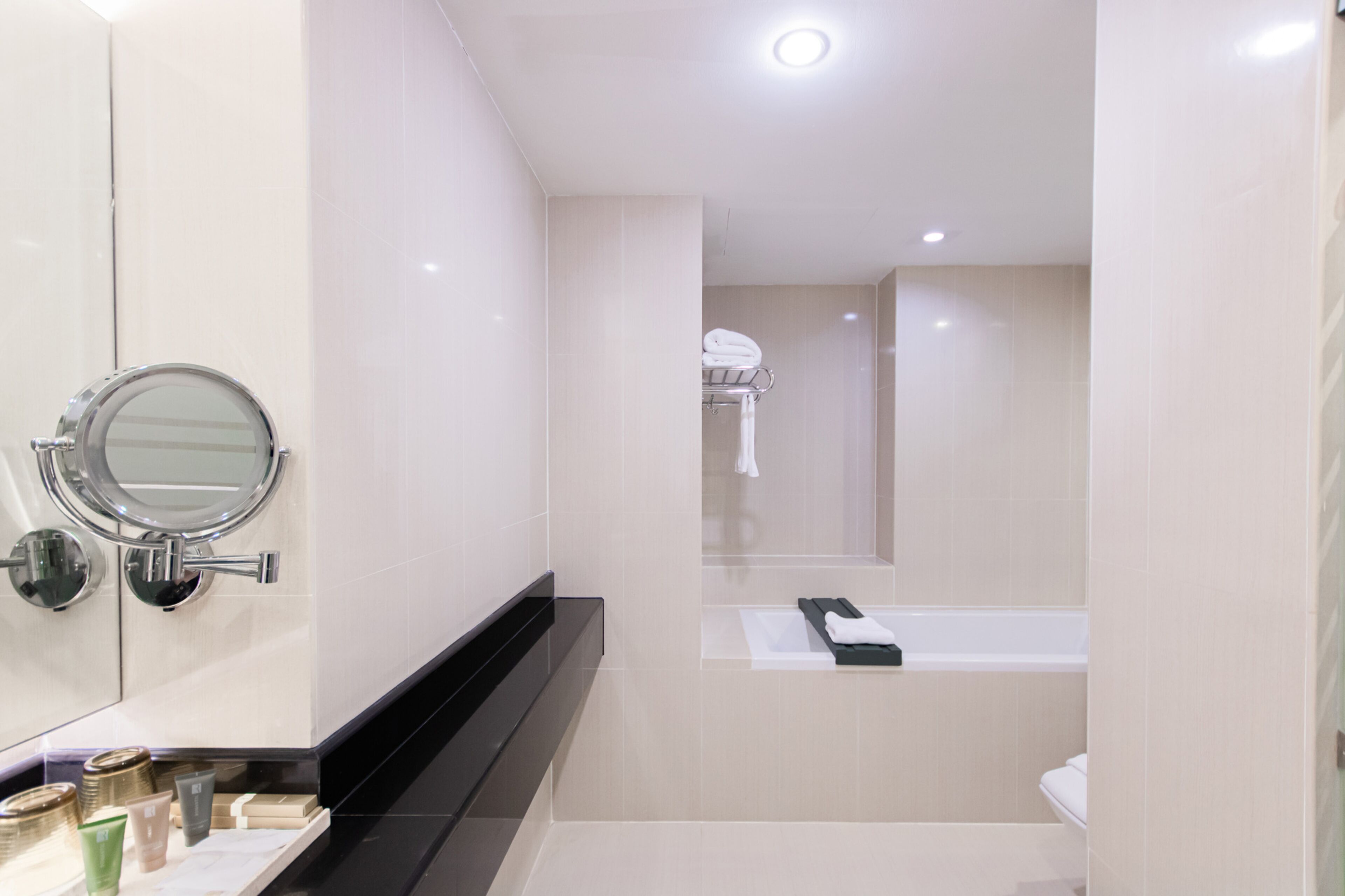 Un baño moderno con un espejo grande, un lavabo y una bañera.