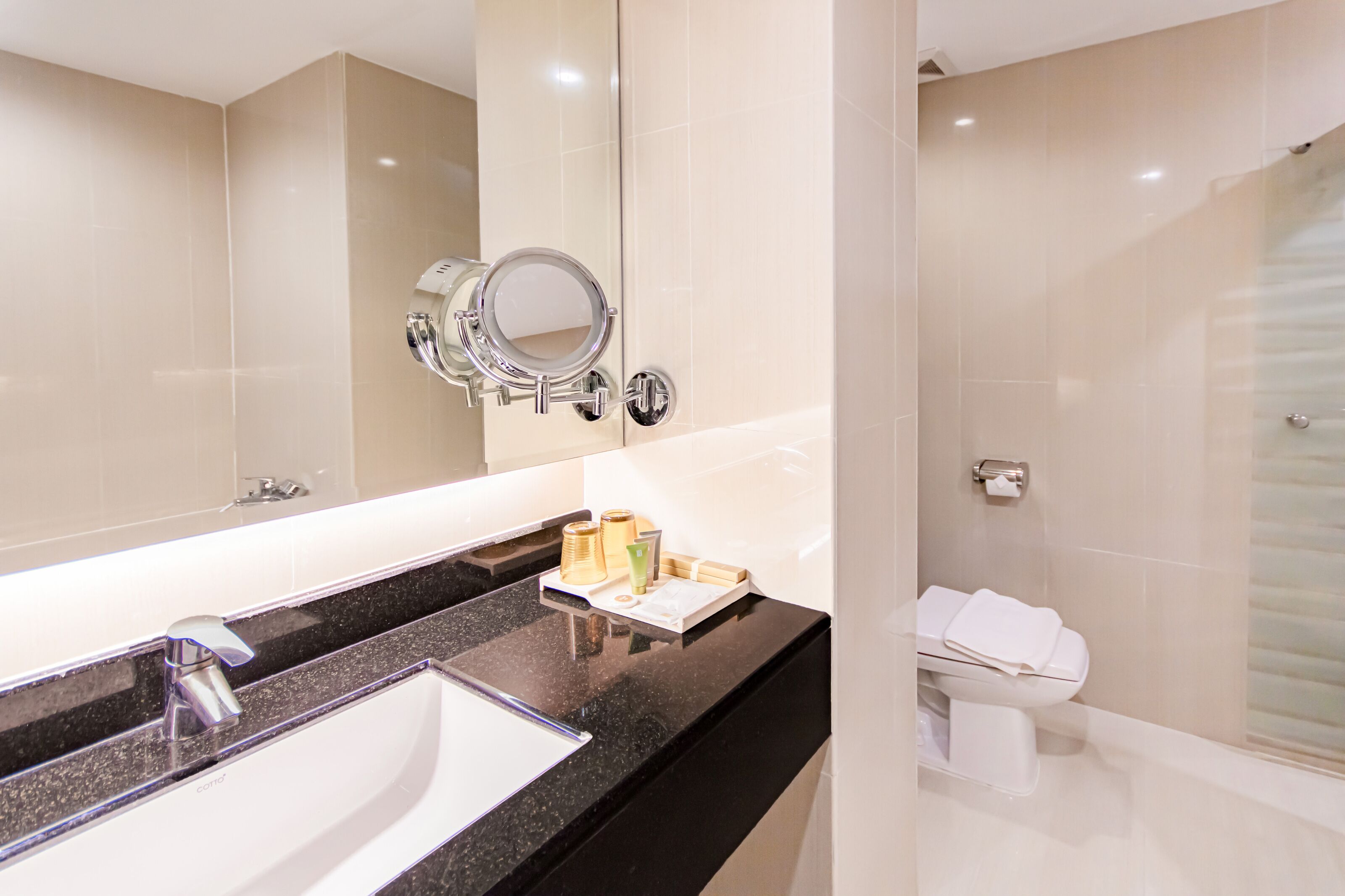 Un baño moderno con un espejo grande, un lavabo y un inodoro.