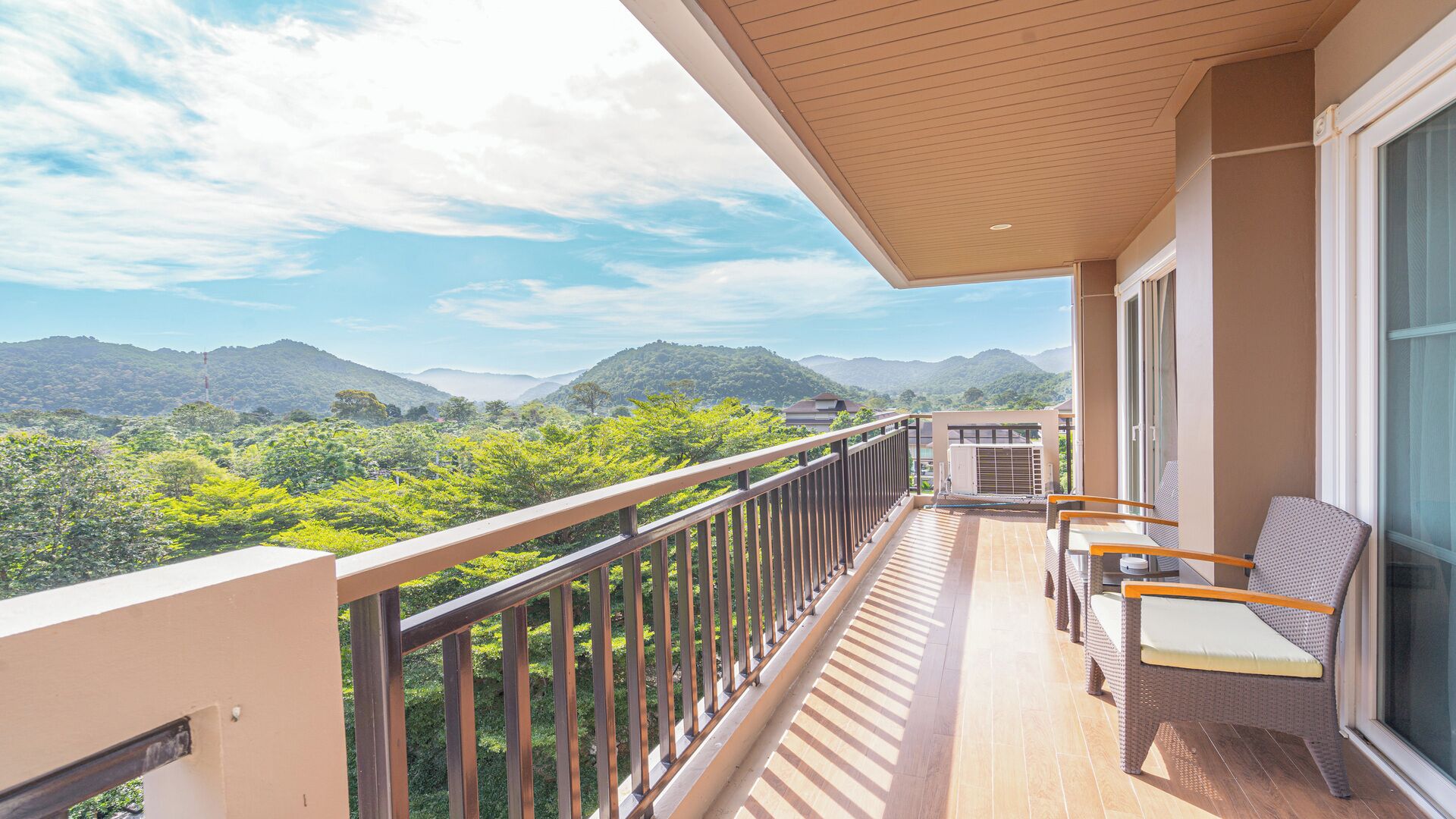 A balcony with a view of mountains, a chair, and a table.