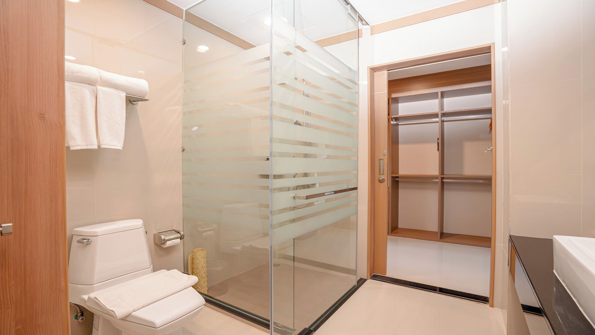 Une salle de bain moderne avec une douche à parois de verre, des toilettes et un meuble-lavabo en bois.