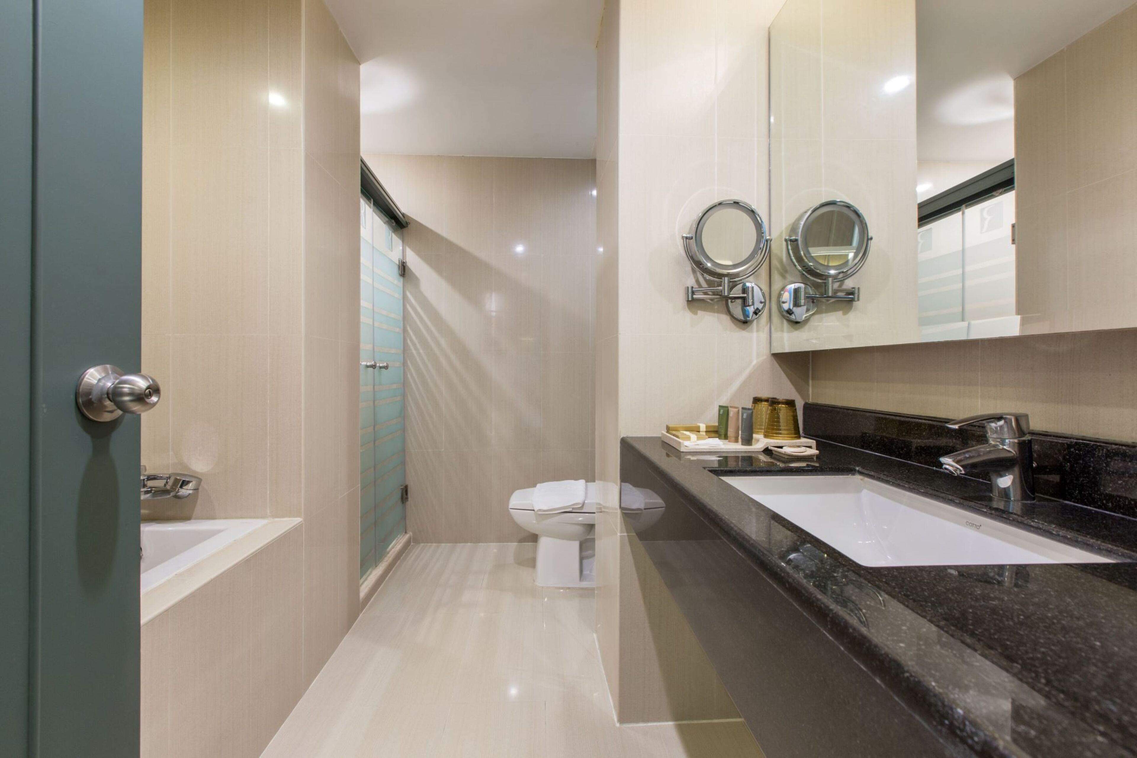 A modern bathroom with a bathtub, two sinks, and a toilet.