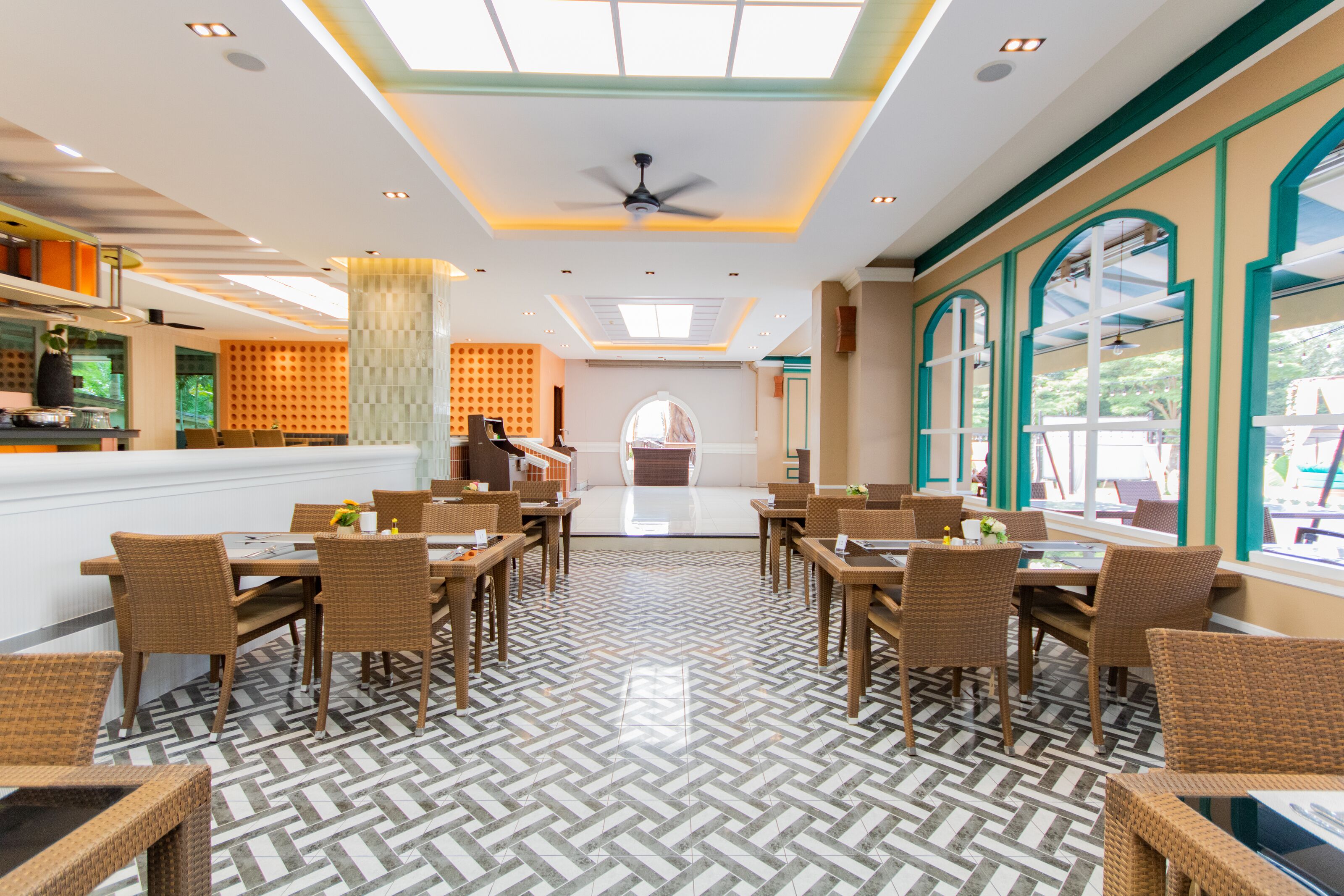 A spacious dining area with high ceilings, a central ceiling fan, and a patterned floor.
