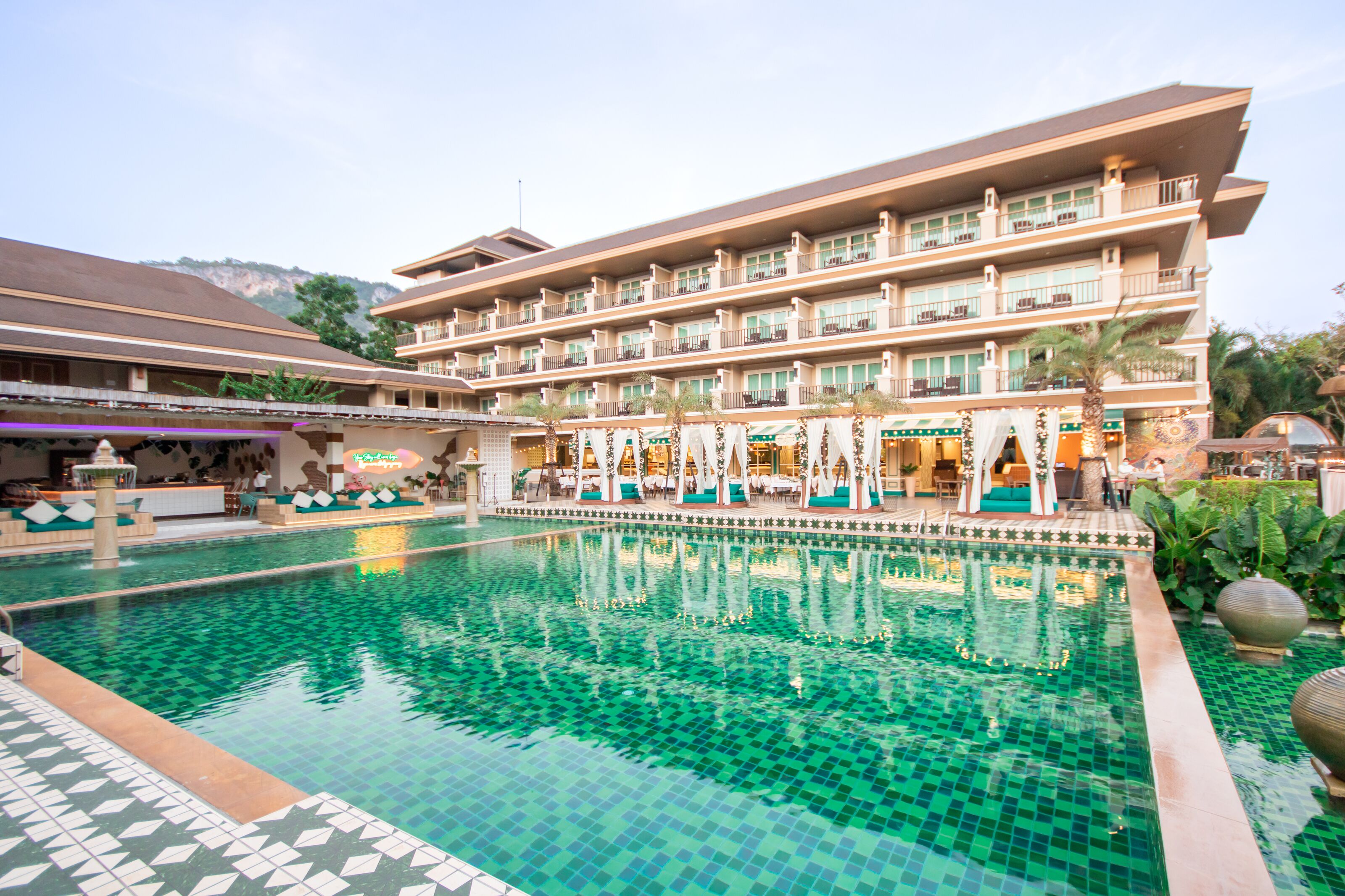 Un hotel con una piscina grande, varios balcones y un diseño arquitectónico moderno.