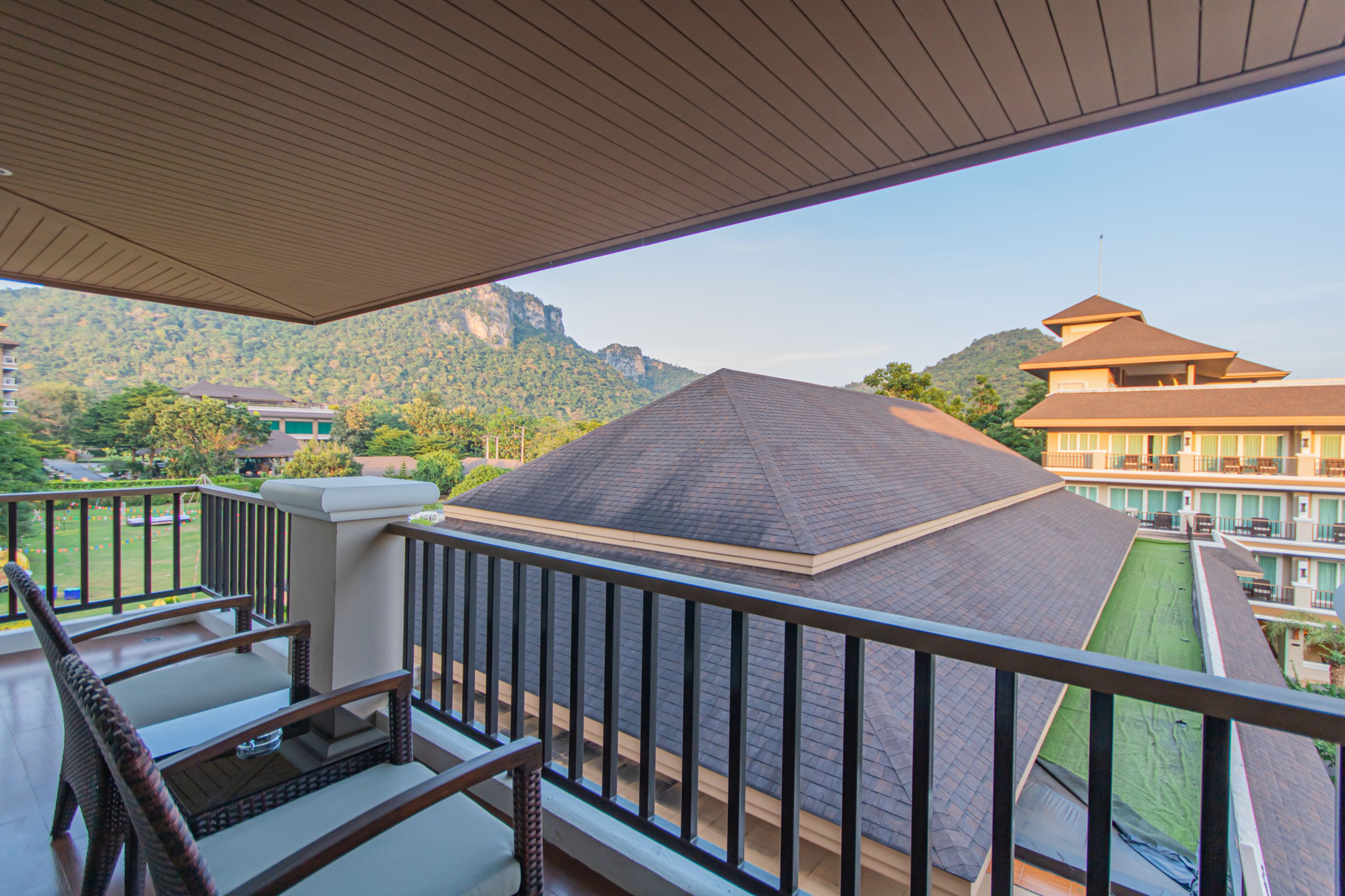 Un balcón con vistas a un paisaje montañoso y un edificio tradicional con tejado al estilo pagoda.