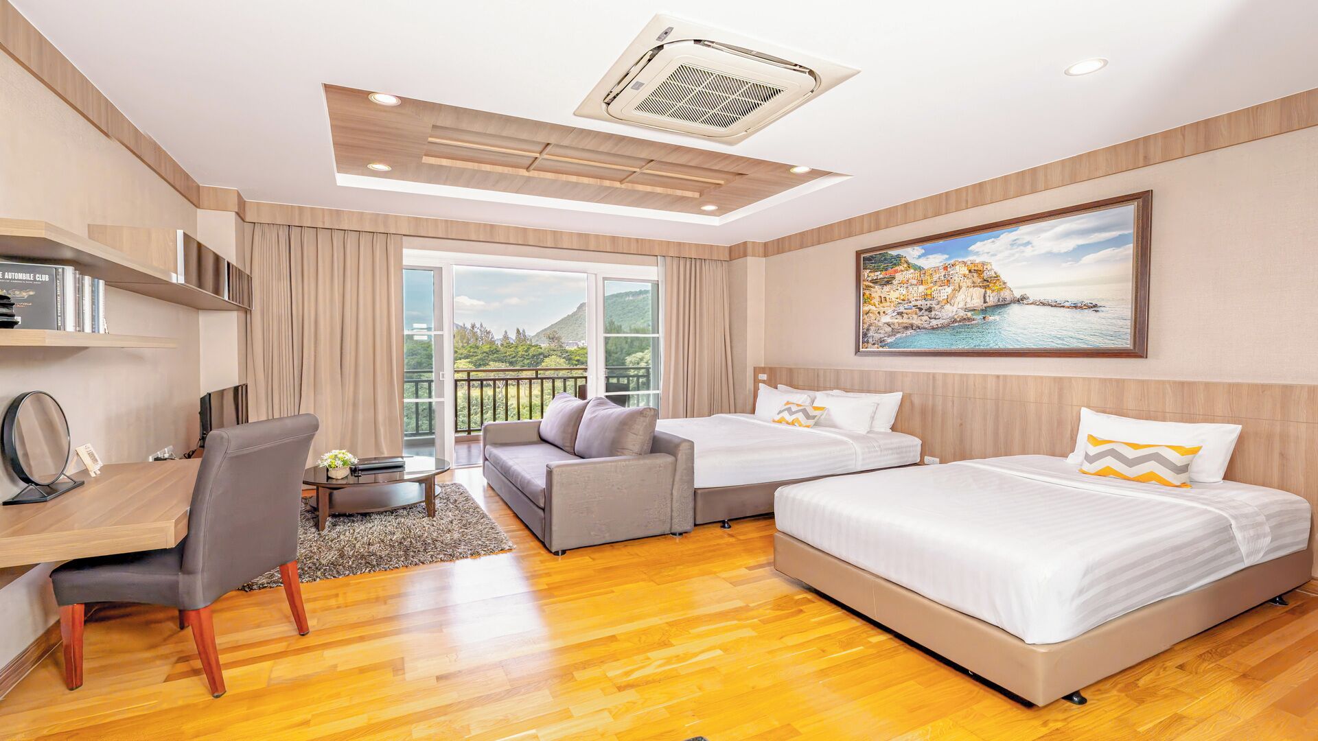 A hotel room with a bed, a sofa, a desk, and a view of the outdoors.