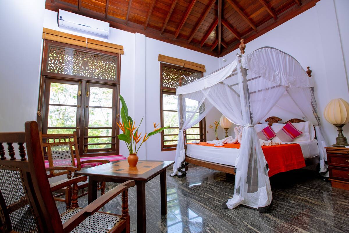 A room with a four-poster bed, a wooden table, and a chair.