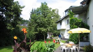 A patio area with potted plants, outdoor furniture, and a yellow umbrella. - Hotel Garni Alt Refrath (Bergisch Gladbach)