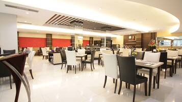 A spacious hotel dining area with multiple tables and chairs, a modern ceiling design, and a clean, well-lit environment.