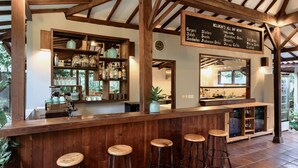 A rustic bar area with wooden beams, a chalkboard menu, and bar stools. - Belukar Villas (Gili Trawangan)
