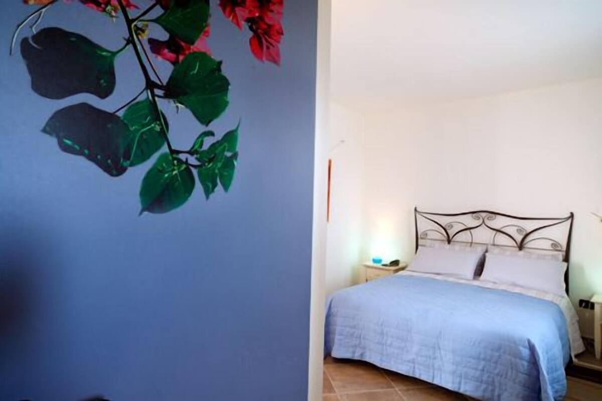Ein Schlafzimmer mit einem Bett, einem Nachttisch und einer Wandpflanze.