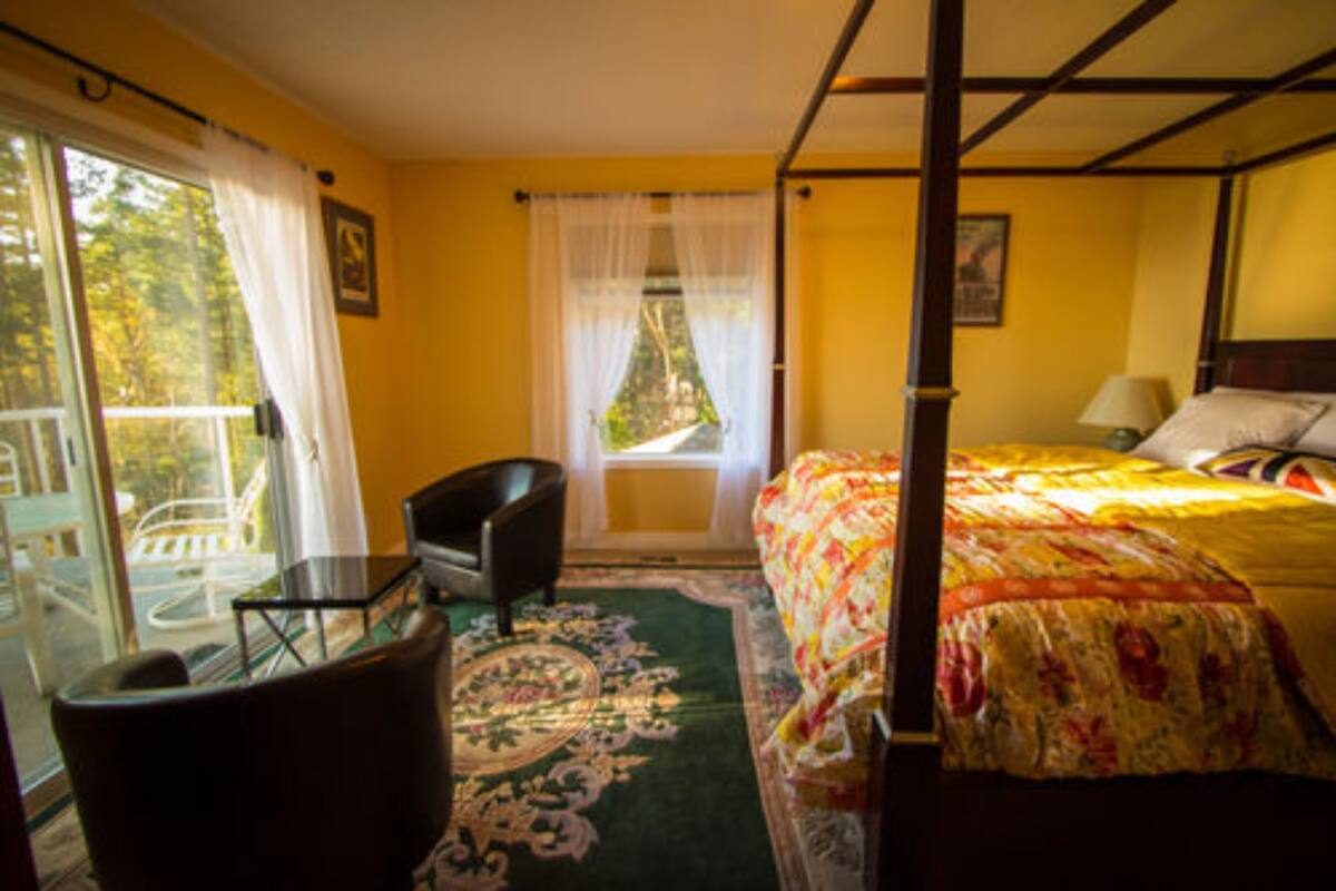 A room with a bed, a chair, a table, and a window with curtains.