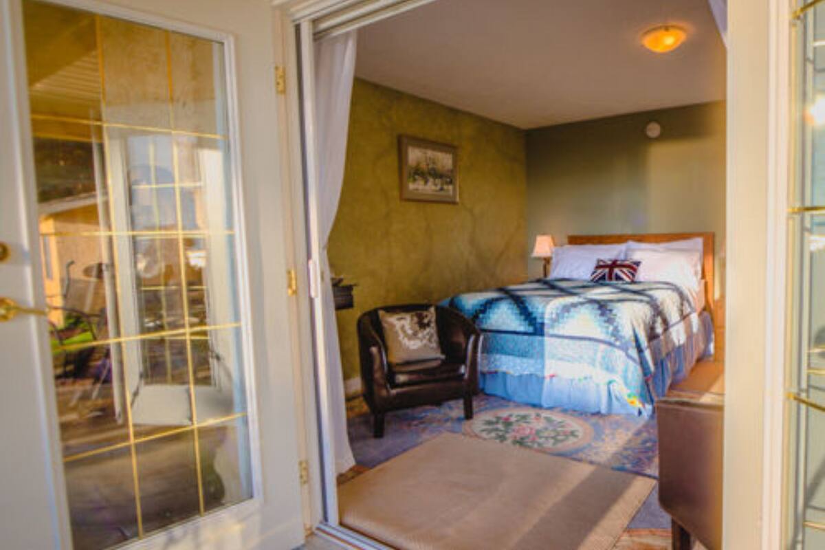 A bedroom with a bed, a chair, and a door leading to another room.
