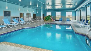 An indoor swimming pool with blue and white lounge chairs, a green frog sculpture, and large windows. - Four Points by Sheraton Fargo Medical Center (Fargo)