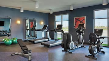 A gym with treadmills, elliptical machines, and exercise balls.