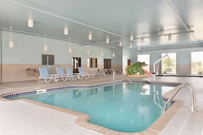 An indoor swimming pool with lounge chairs, a children's play area, and a view of the outdoors. - Four Points by Sheraton Fargo Medical Center (Fargo)