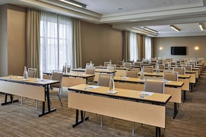 A conference room with rows of tables and chairs, large windows with curtains, and a flat-screen TV on the wall. - Four Points by Sheraton Fargo Medical Center (Fargo)