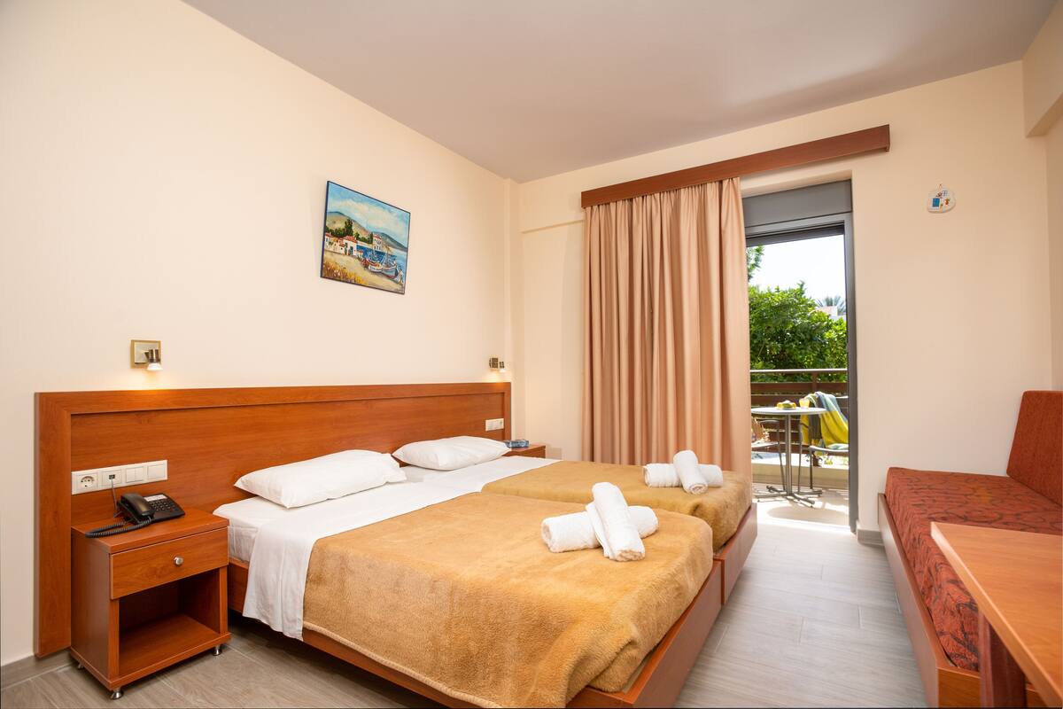 A hotel room with two beds, a wooden headboard, a bedside table with a phone, and a painting on the wall.
