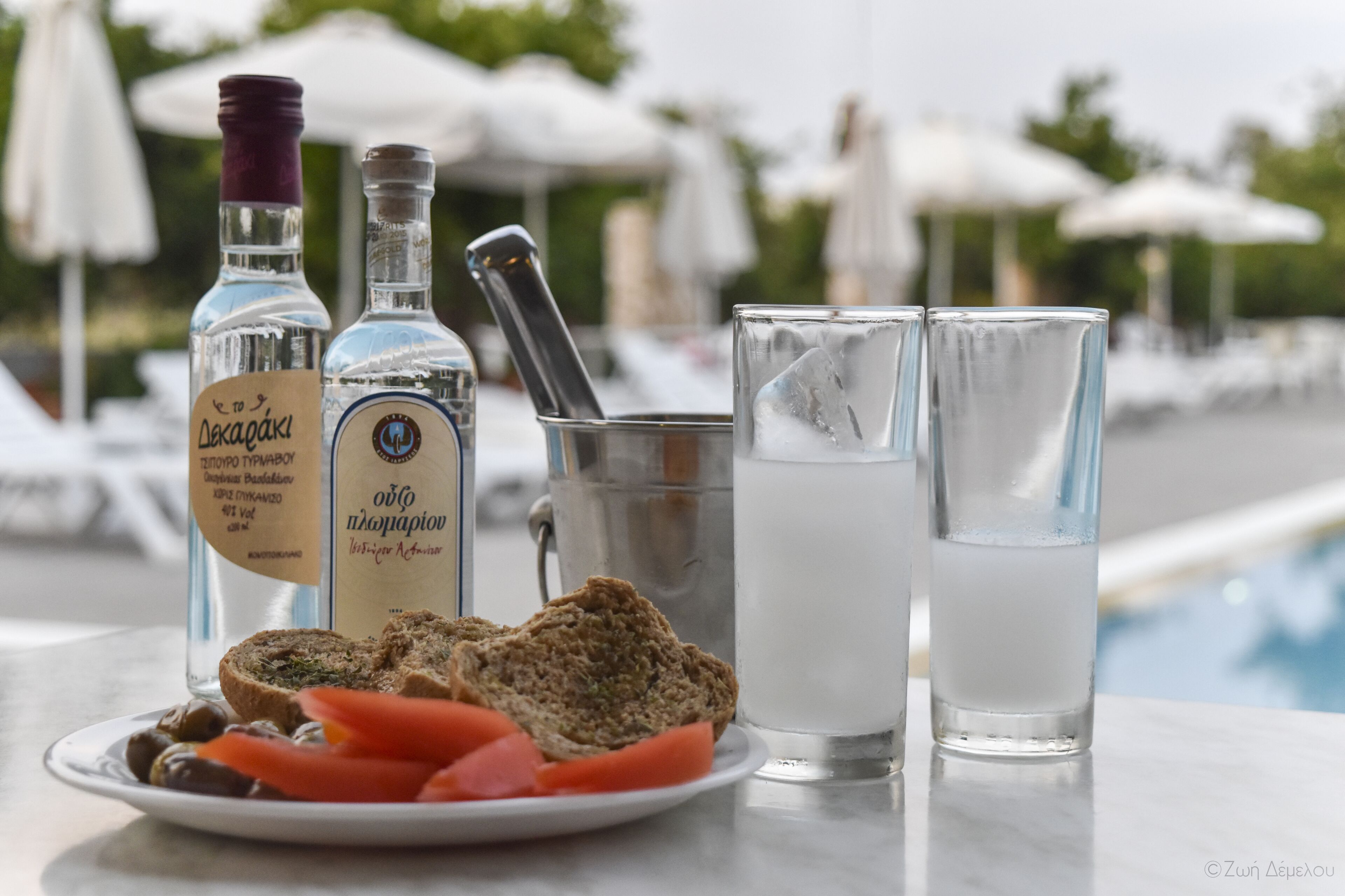 A table with two bottles, a glass pitcher, and two glasses with ice cubes.