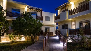 Un edificio moderno de varios pisos con balcones, una escalera central e ingreso bien iluminado.