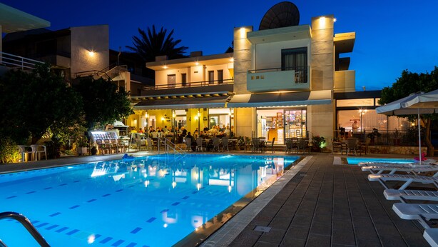 Una piscina con sillas de descanso, un área de bar y un edificio con cúpula y múltiples ventanas.