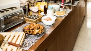 Un bufé de desayuno con diferentes alimentos, un tostador y un espejo en la pared.
