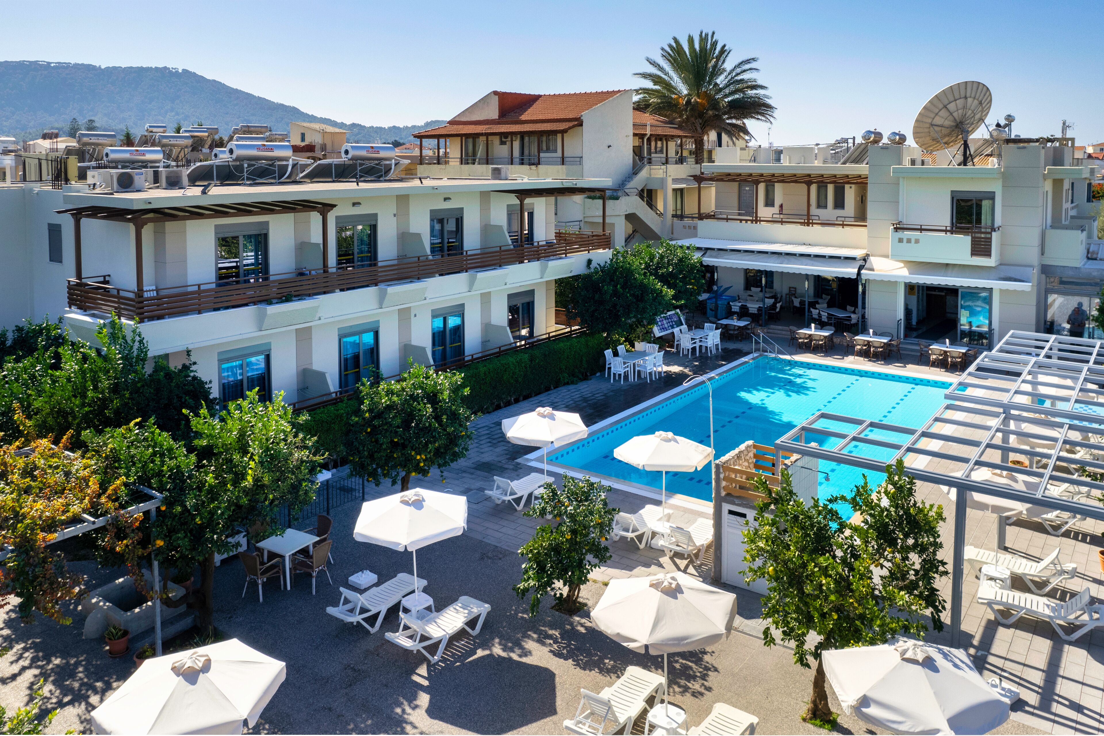 A hotel with a swimming pool, outdoor seating, and a view of the mountains.