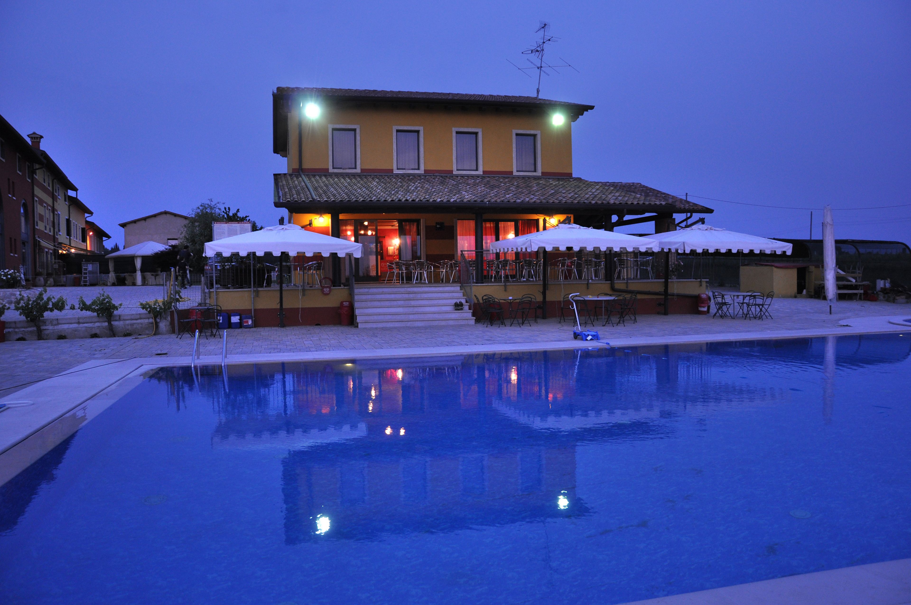 A hotel with a swimming pool, outdoor seating, and a well-lit entrance.